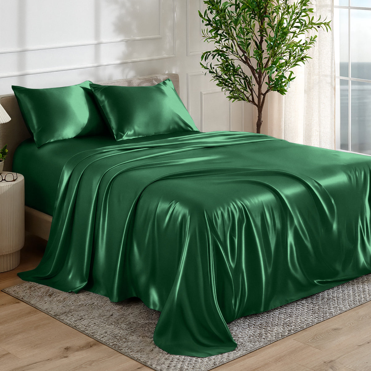 Satin sheet set on a bed in a bedroom with a plant and window in the background.