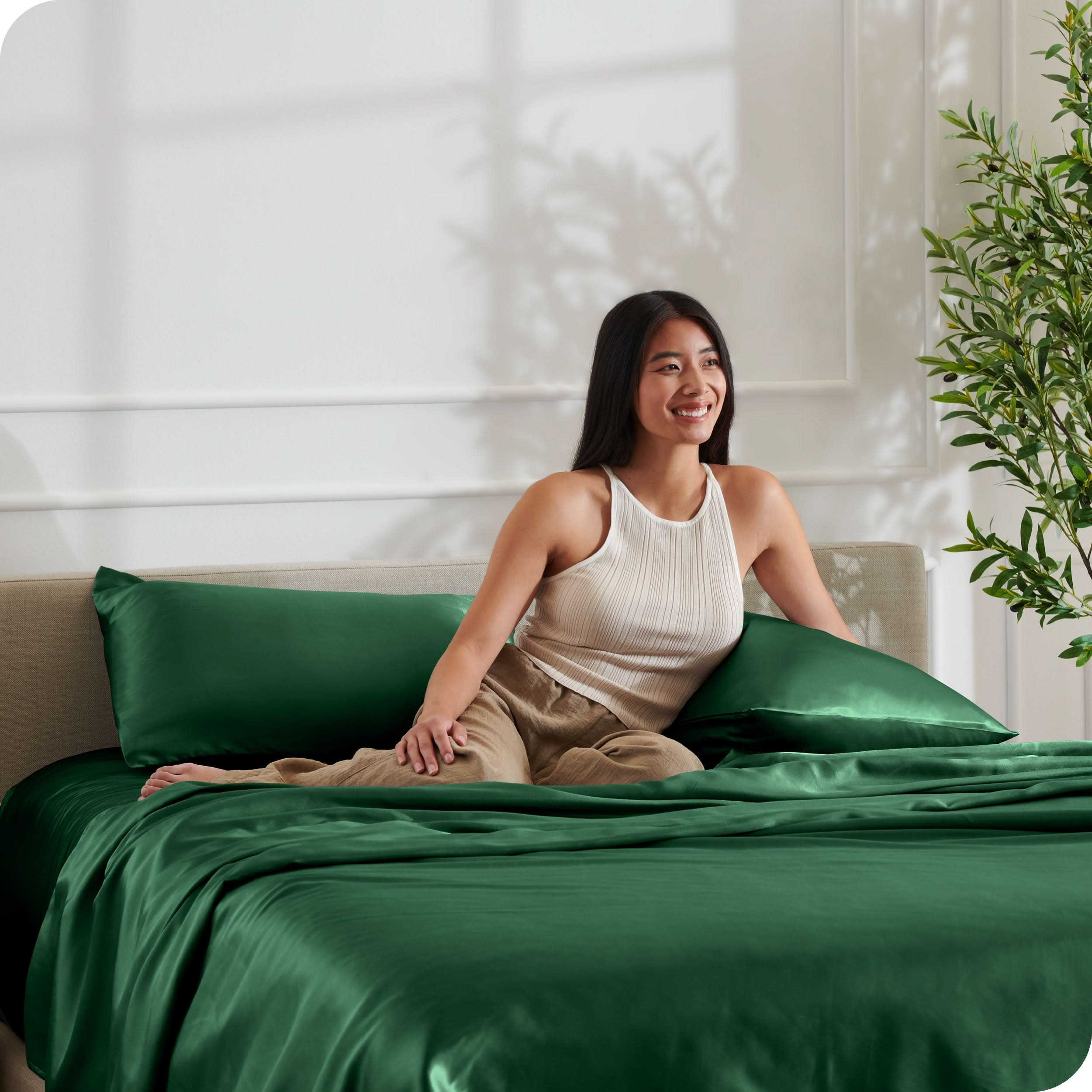 A woman is resting on a bed make with satin sheets