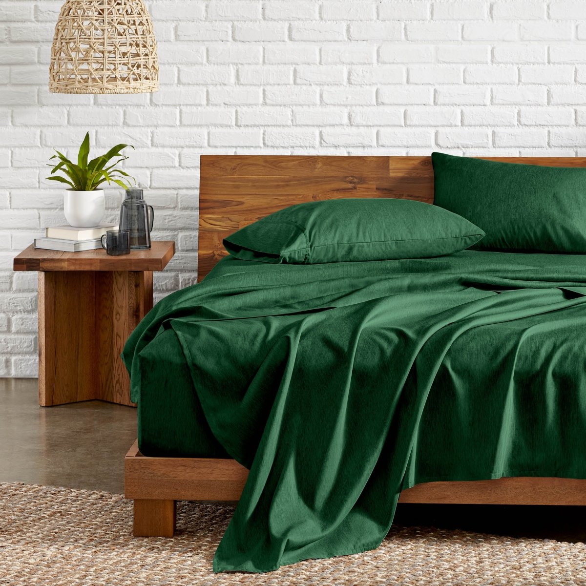 Bedroom with wooden bed, nightstand, and white brick wall.
