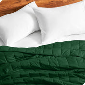 Close up of a weighted blanket on a bed next to pillows