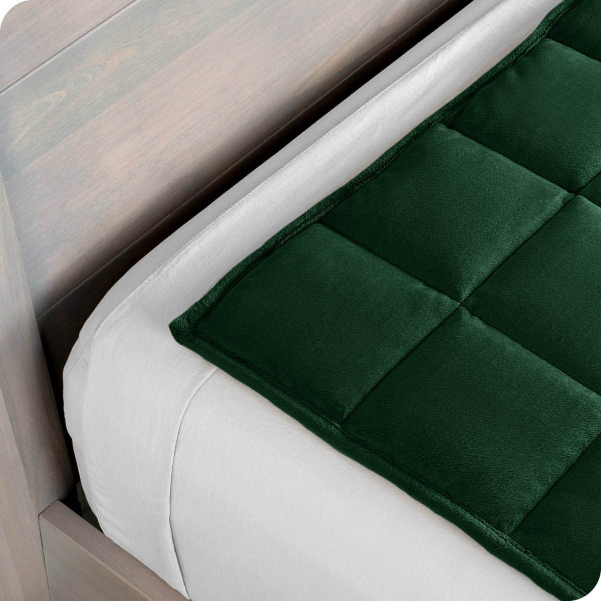 Close up of a weighted blanket on top of a bed made with white sheets