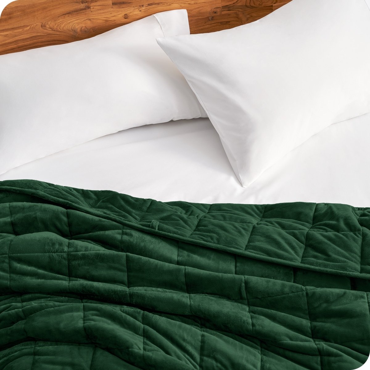 Close up of a weighted blanket on a bed next to pillows