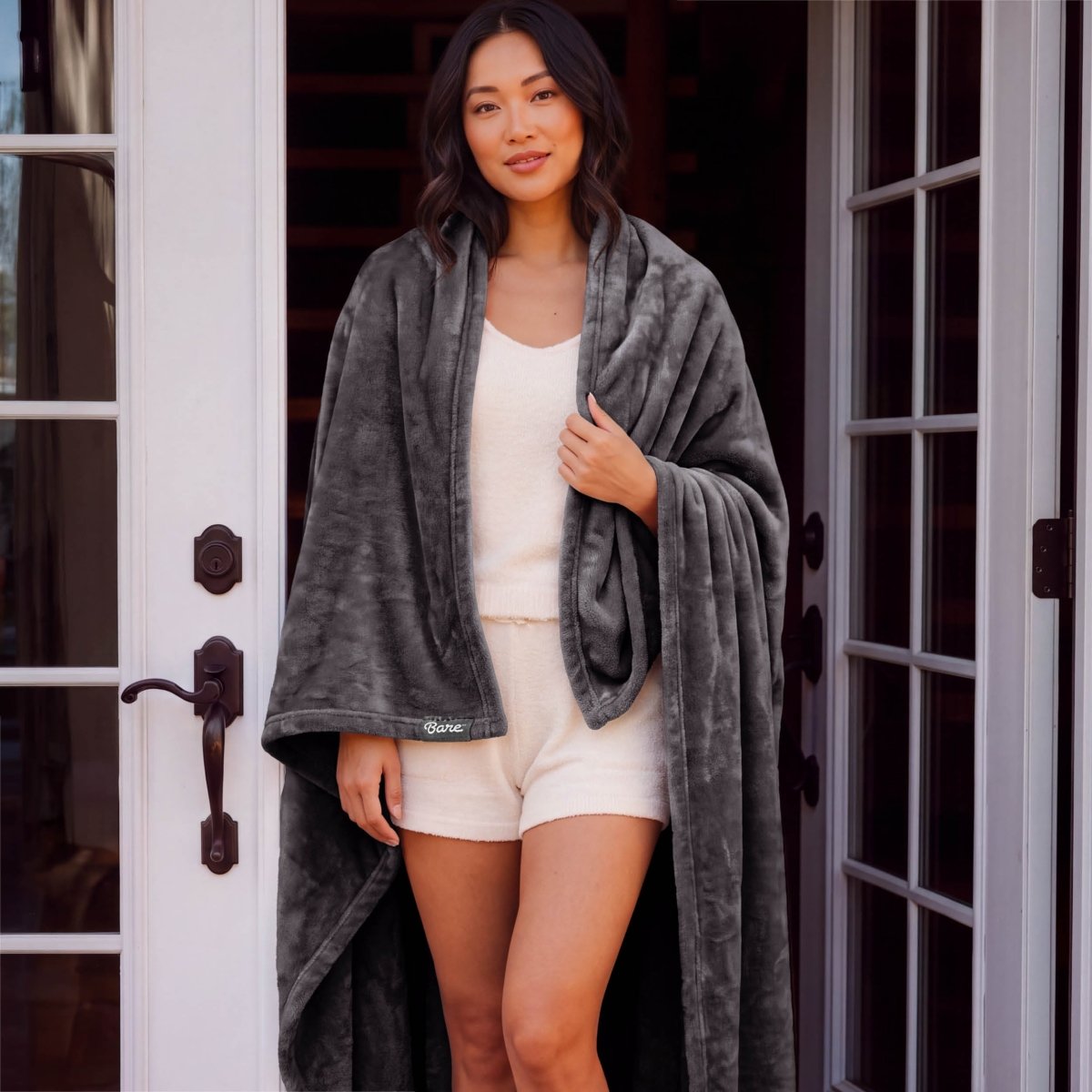 A woman standing with a microplush blanket wrapped around her