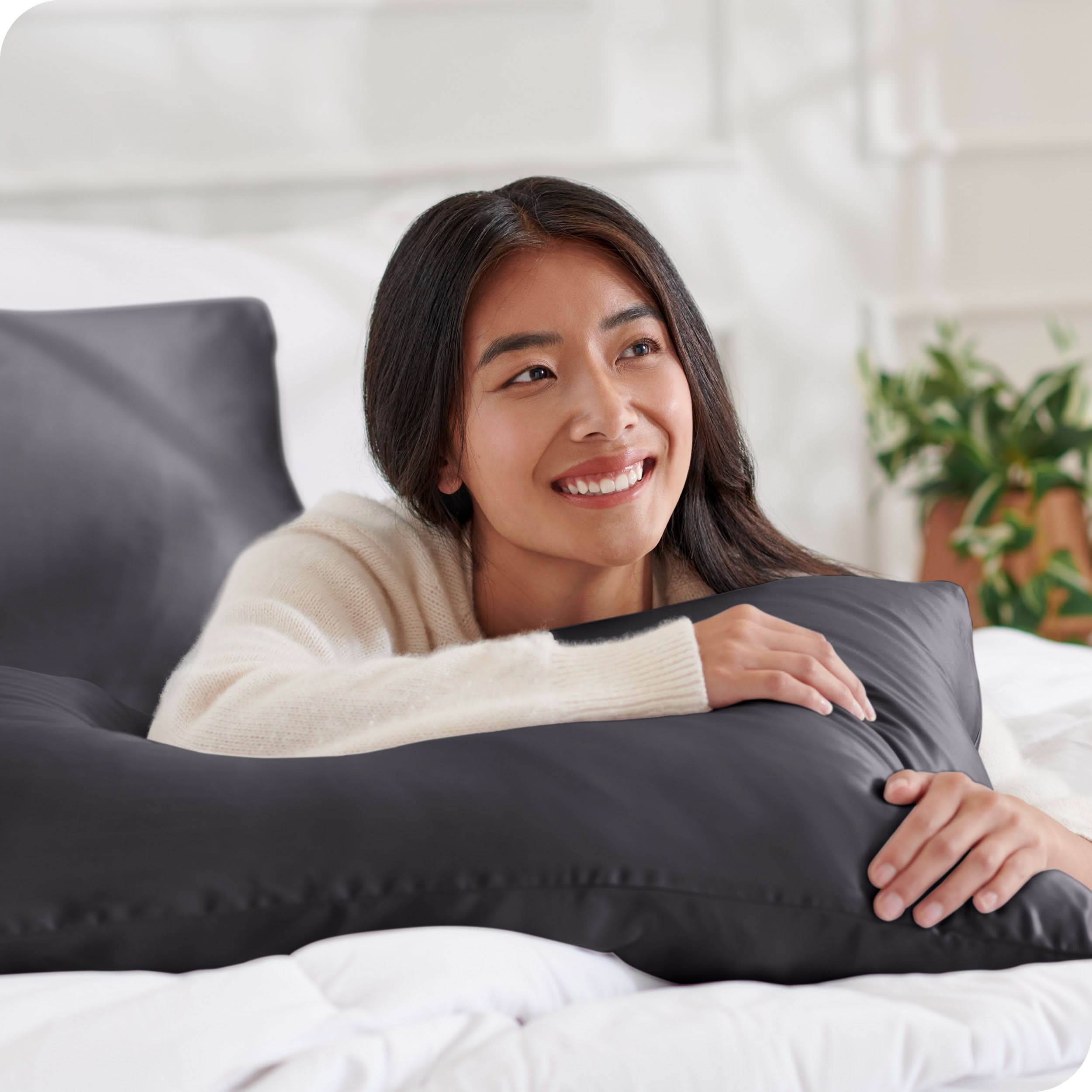 A woman on a bed with a silk pillowcase covered pillow