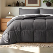 Comforter on a bed in a bedroom setting with a wooden nightstand and decorative items.