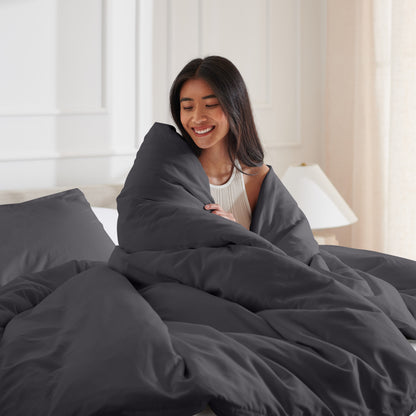 Woman smiling under duvet cover set in a bedroom setting