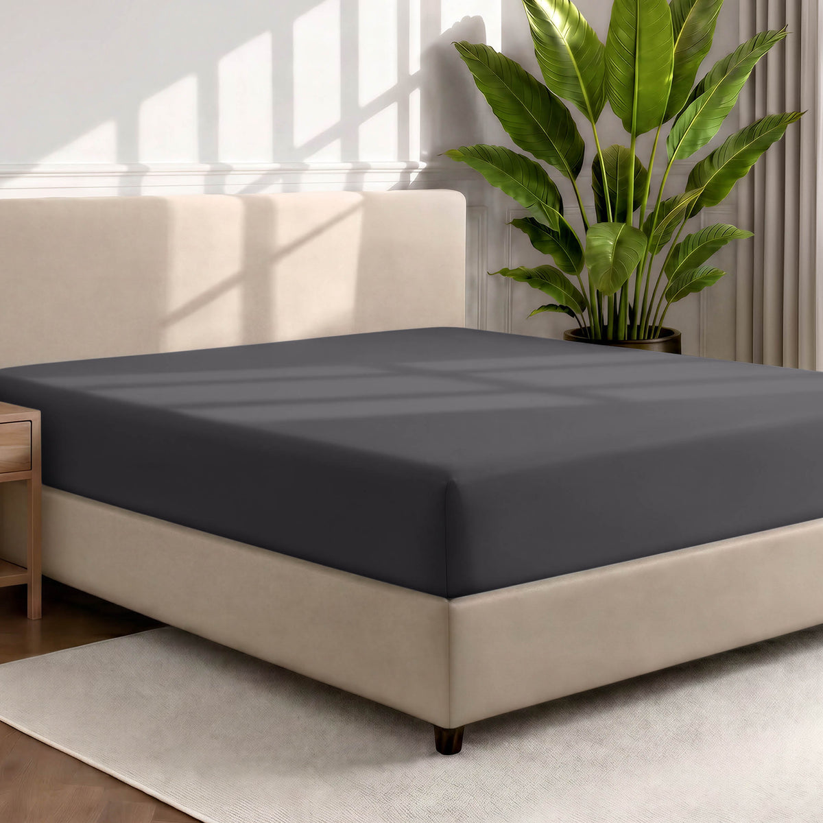 Man adjusting fitted sheet on a bed with white pillows.