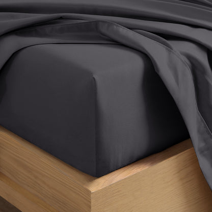 Close up of the corner of a mattress with a fitted sheet and flat sheet on it