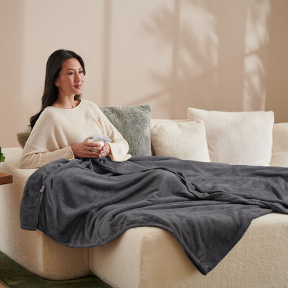 A woman sitting on a couch with a microplush blanket on her lap