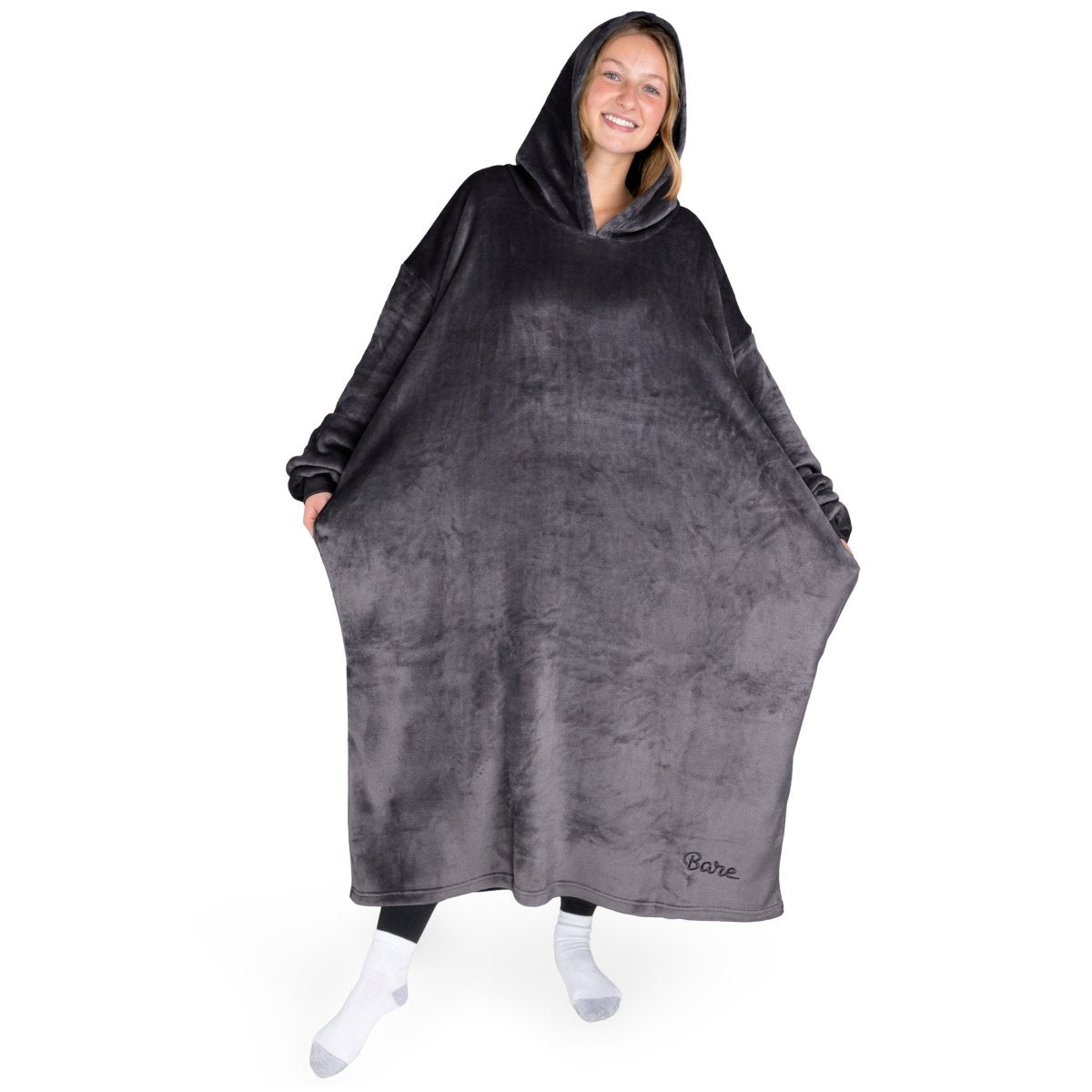 An adult is standing while wearing a long microplush wearable blanket