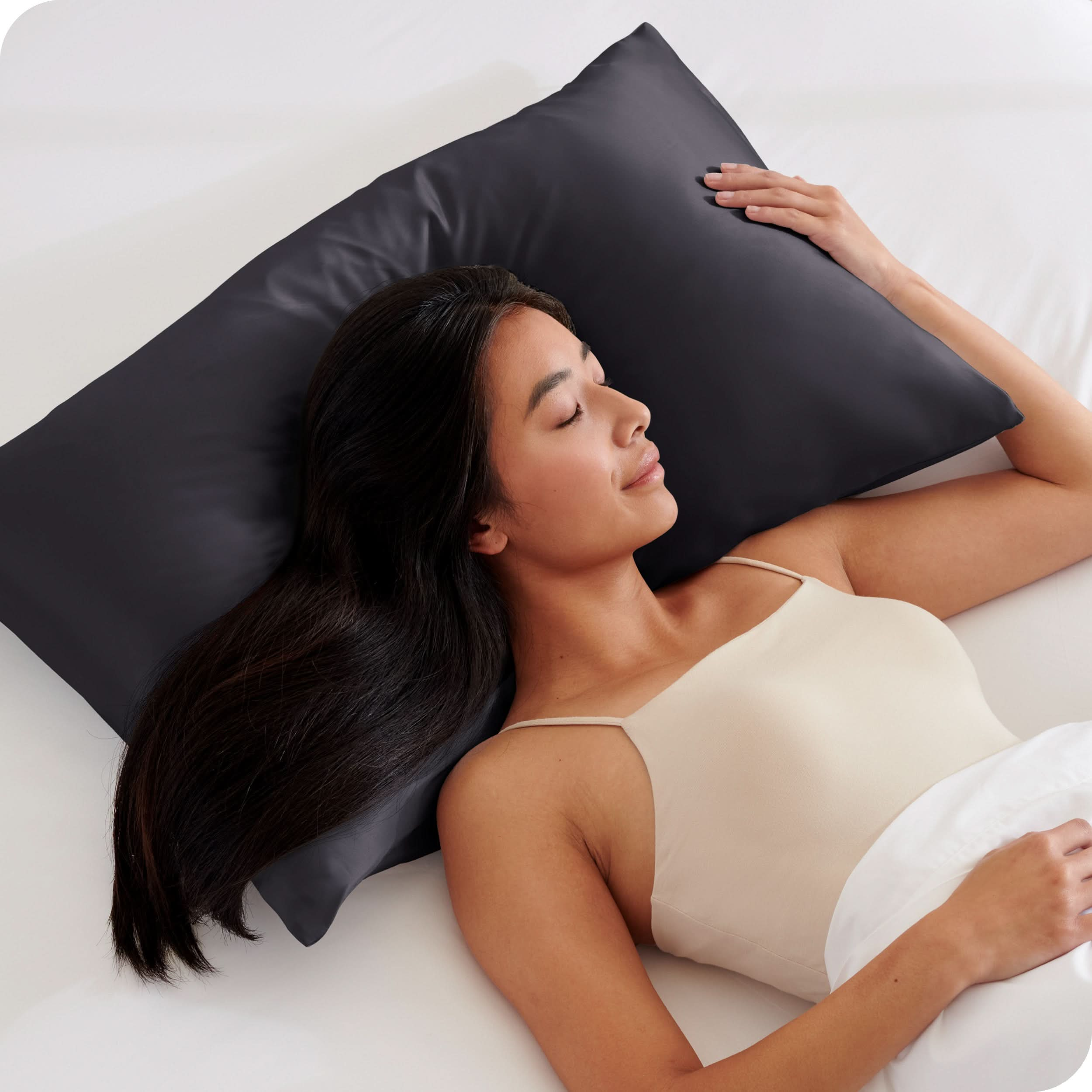 A woman is sleeping on a pillow with a satin pillowcase