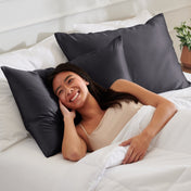 Woman lying on a bed with satin pillows and white bedding