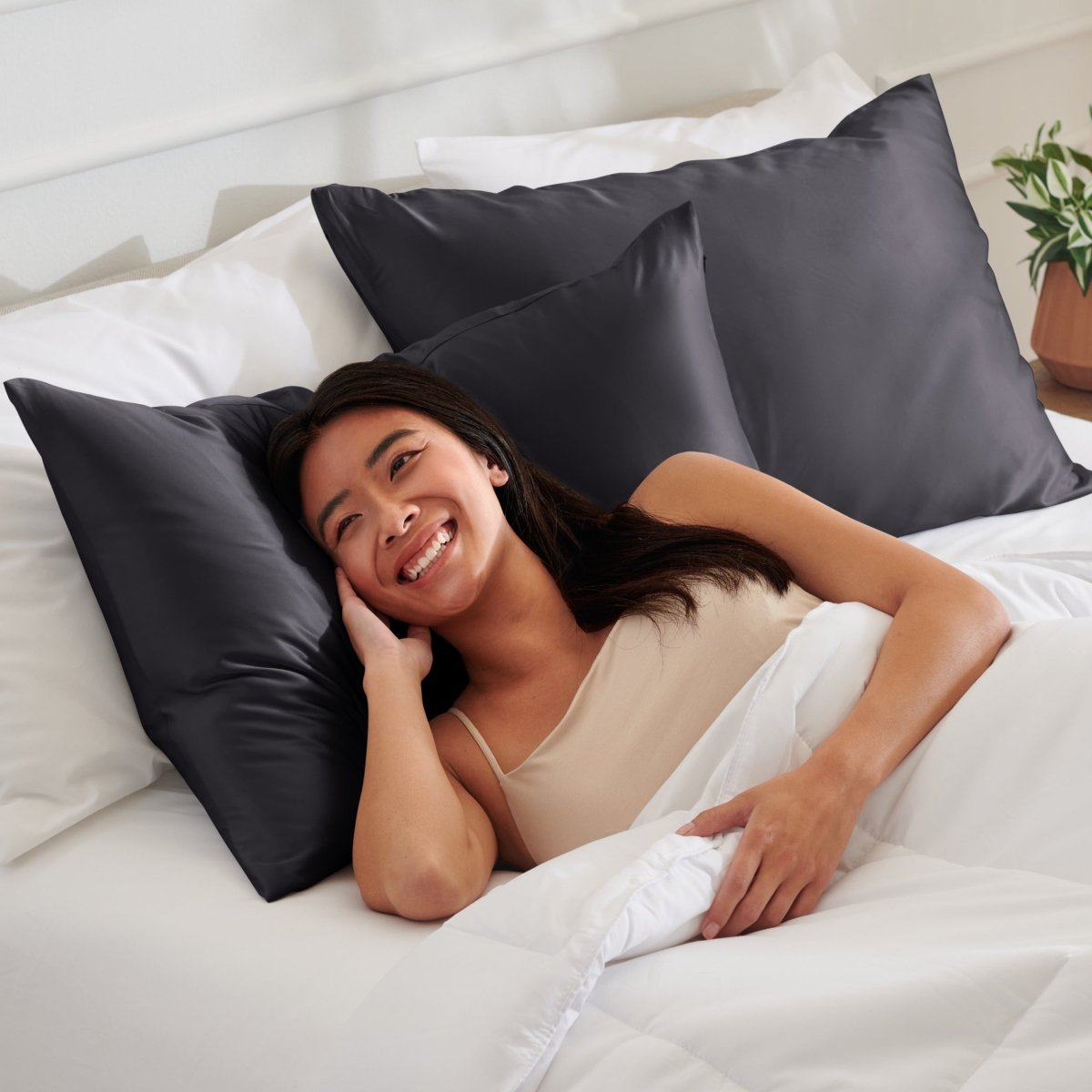 Woman lying on a bed with satin pillows and white bedding