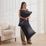 Woman holding 2 pillows with satin pillowcases on them