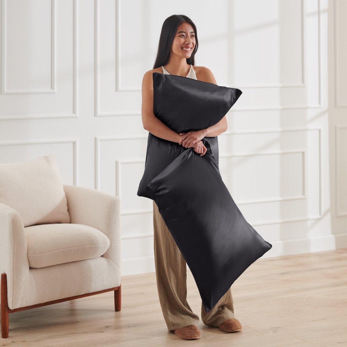 Woman holding 2 pillows with satin pillowcases on them