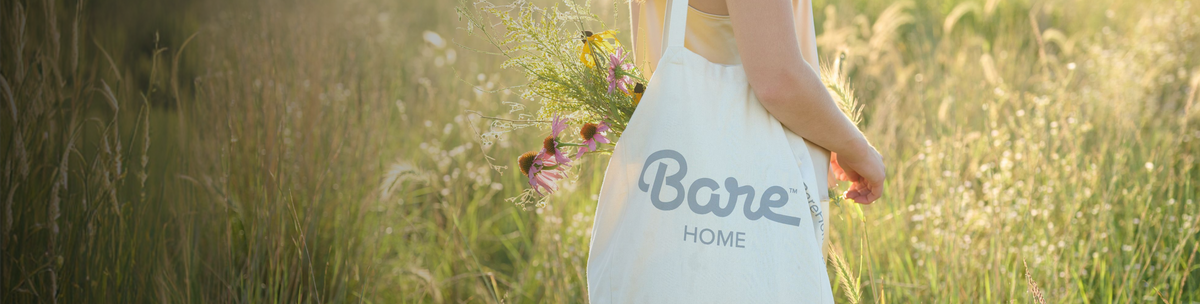 Woman walking outdoors in a field holding a Bare Home tote bag