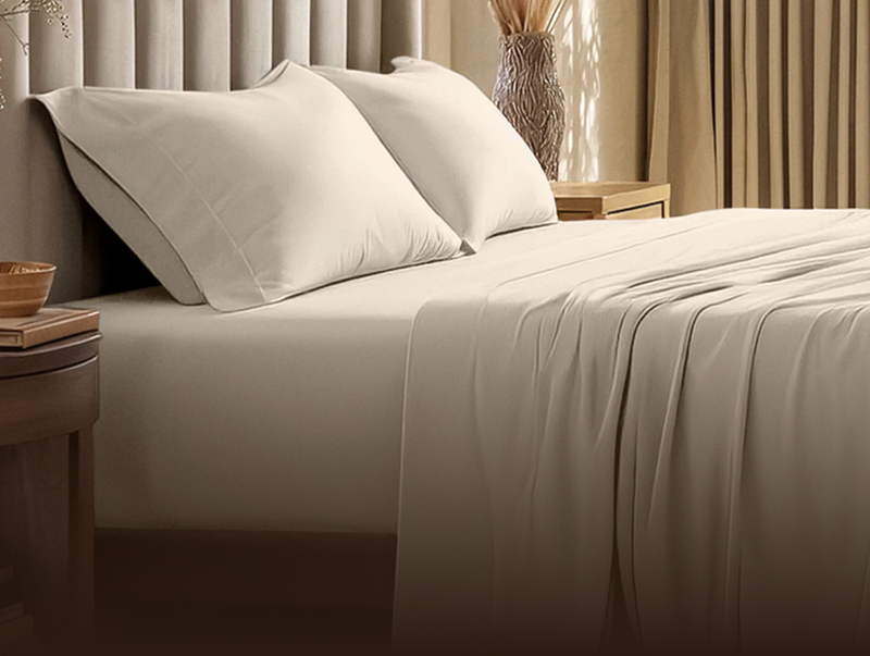 Neatly made bed with beige sheets and pillows