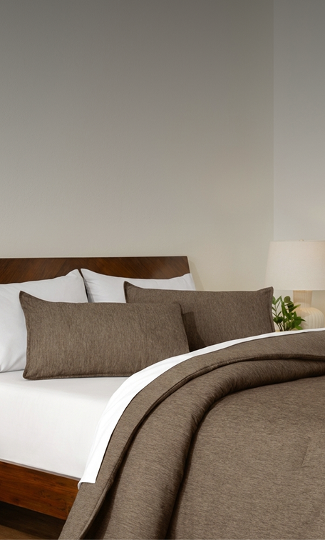 A bed made with a track stitch comforter and white sheets