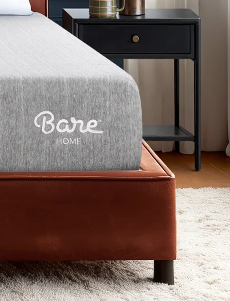 Gray fabric folded on a bed with tan leather headboard and Bare Home logo review