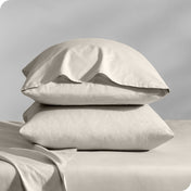 Pillows inside percale pillowcases stacked on a bed