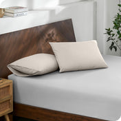 Diagonal view of modern wood bed with a fitted sheet and pillowcases

