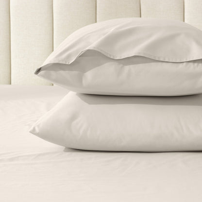 Two pillows stacked on a bed with percale pillowcases on them