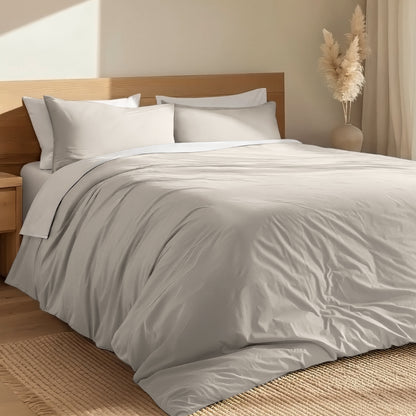 Bed with percale duvet cover set and wooden headboard in a room with a vase and decorative items.