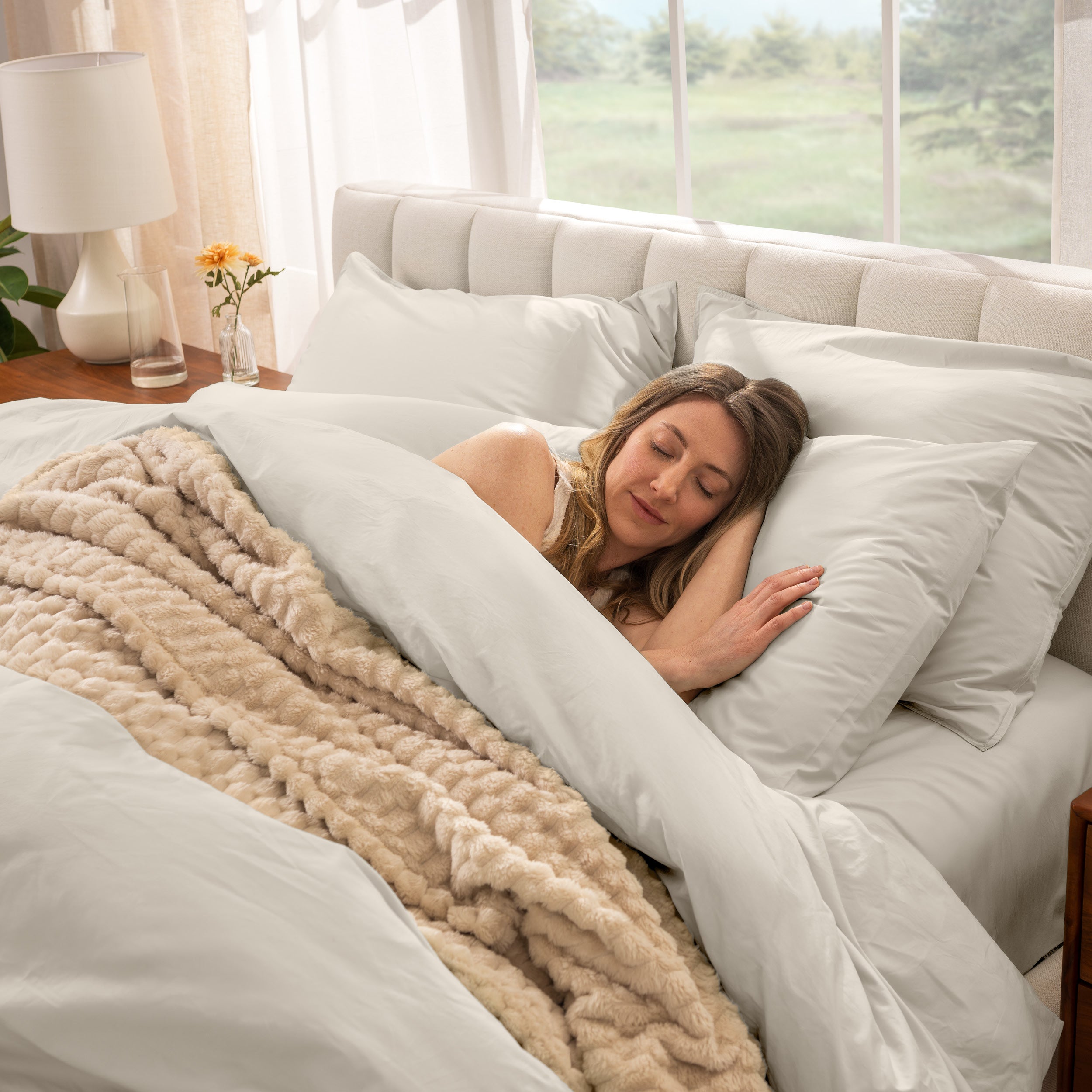 Woman sleeping in a bed with percale bedding and beige blanket