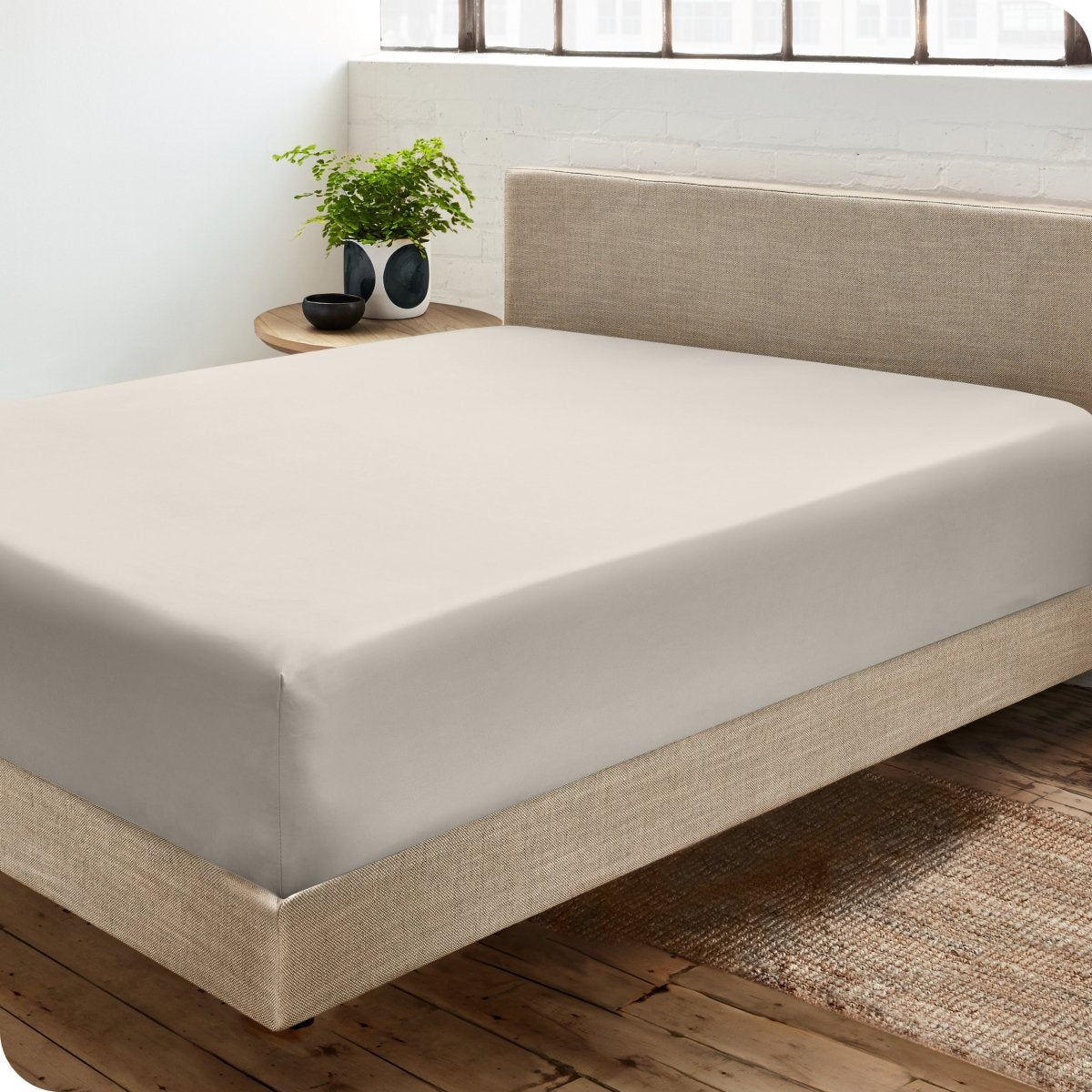 Diagonal view of modern bedroom with a sateen fitted sheet on the bed