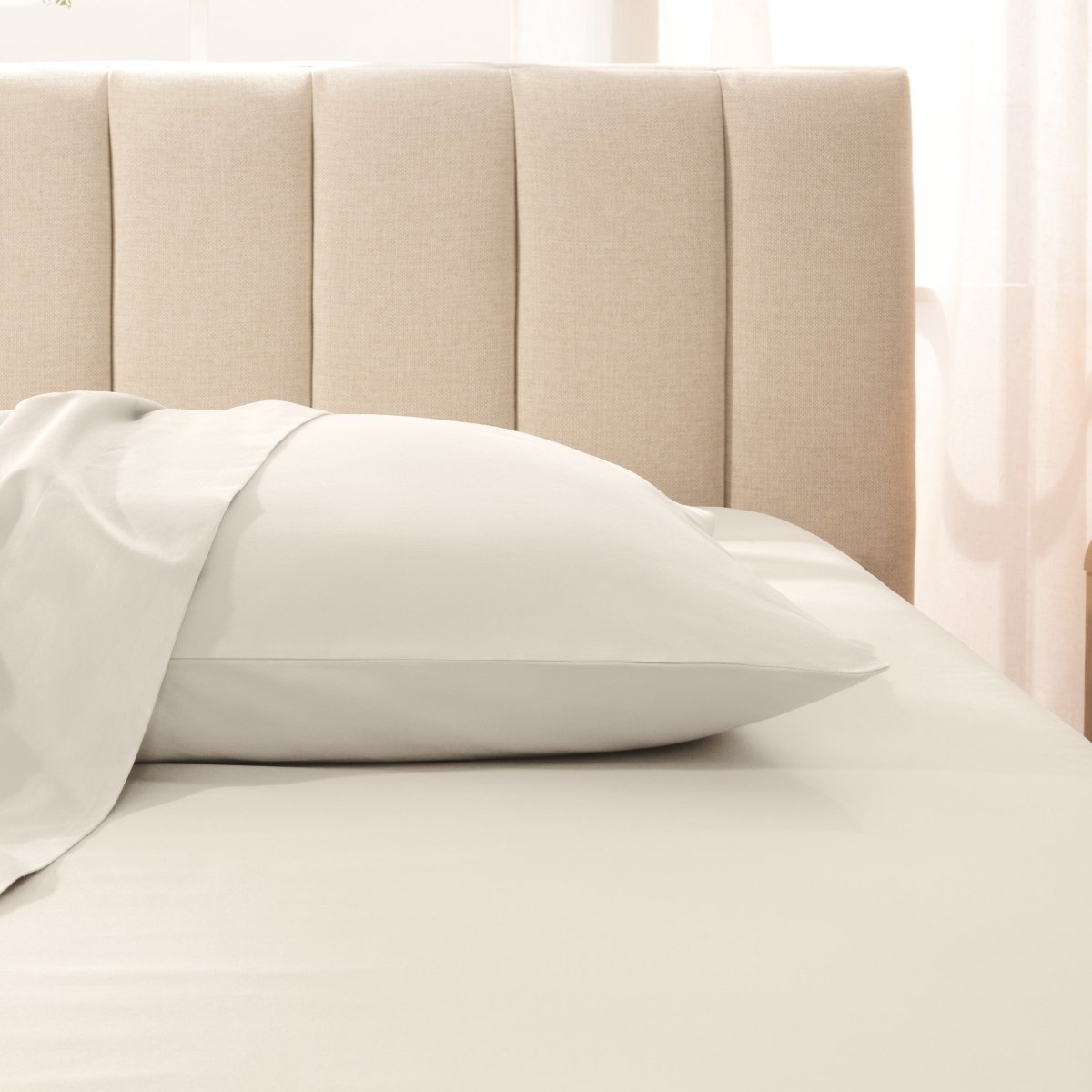 Sateen pillowcase on a bed with a beige headboard