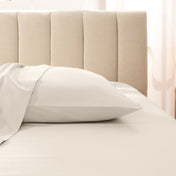 Sateen pillowcase on a bed with a beige headboard