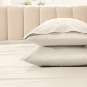 Two pillows stacked on a bed with a beige headboard.