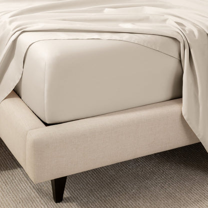 A close-up of the corner of a bed with a fitted sheet and matching flat sheet.