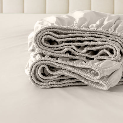 Folded fitted sheet on a bed with a neutral background