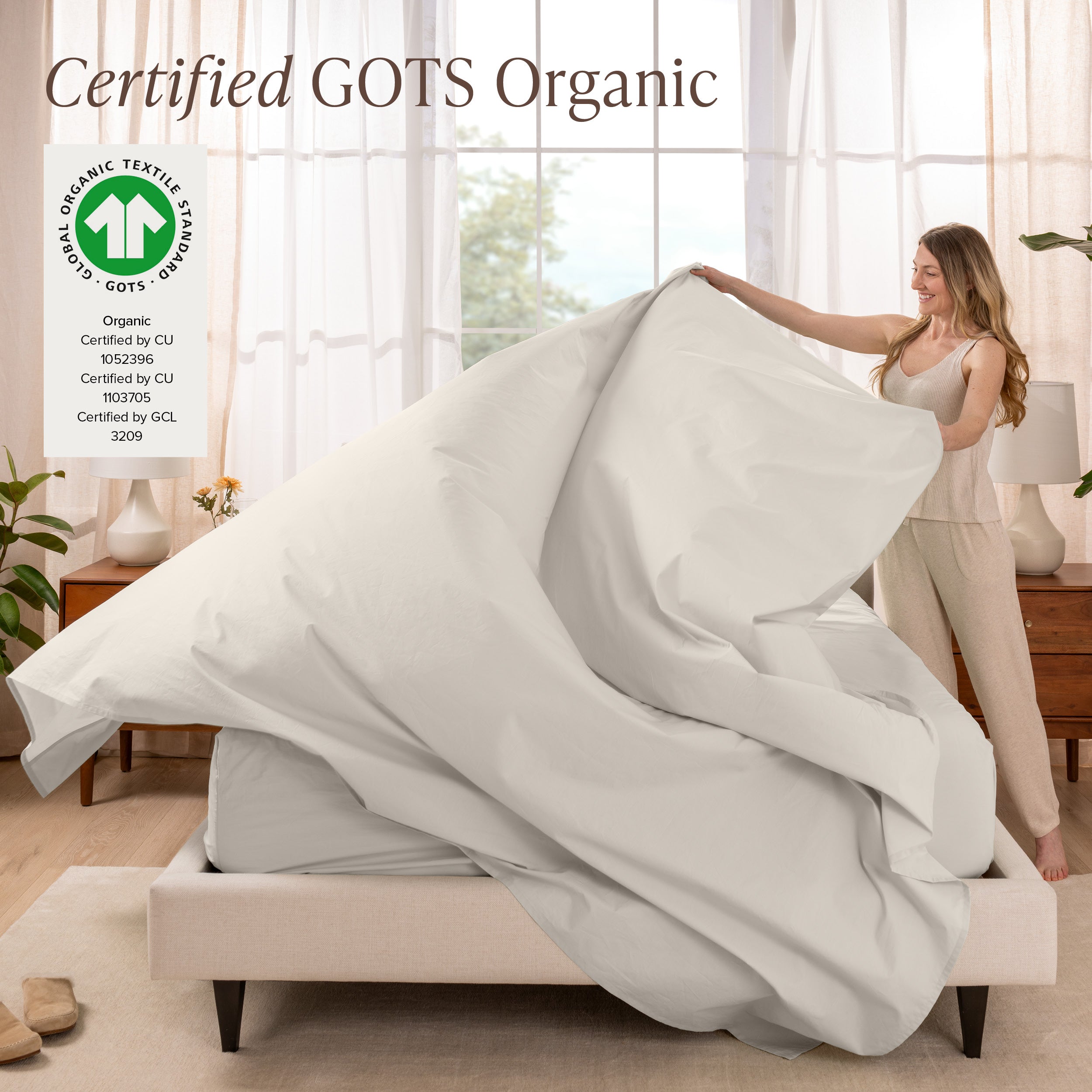 A woman is making a bed with organic cotton percale sheets