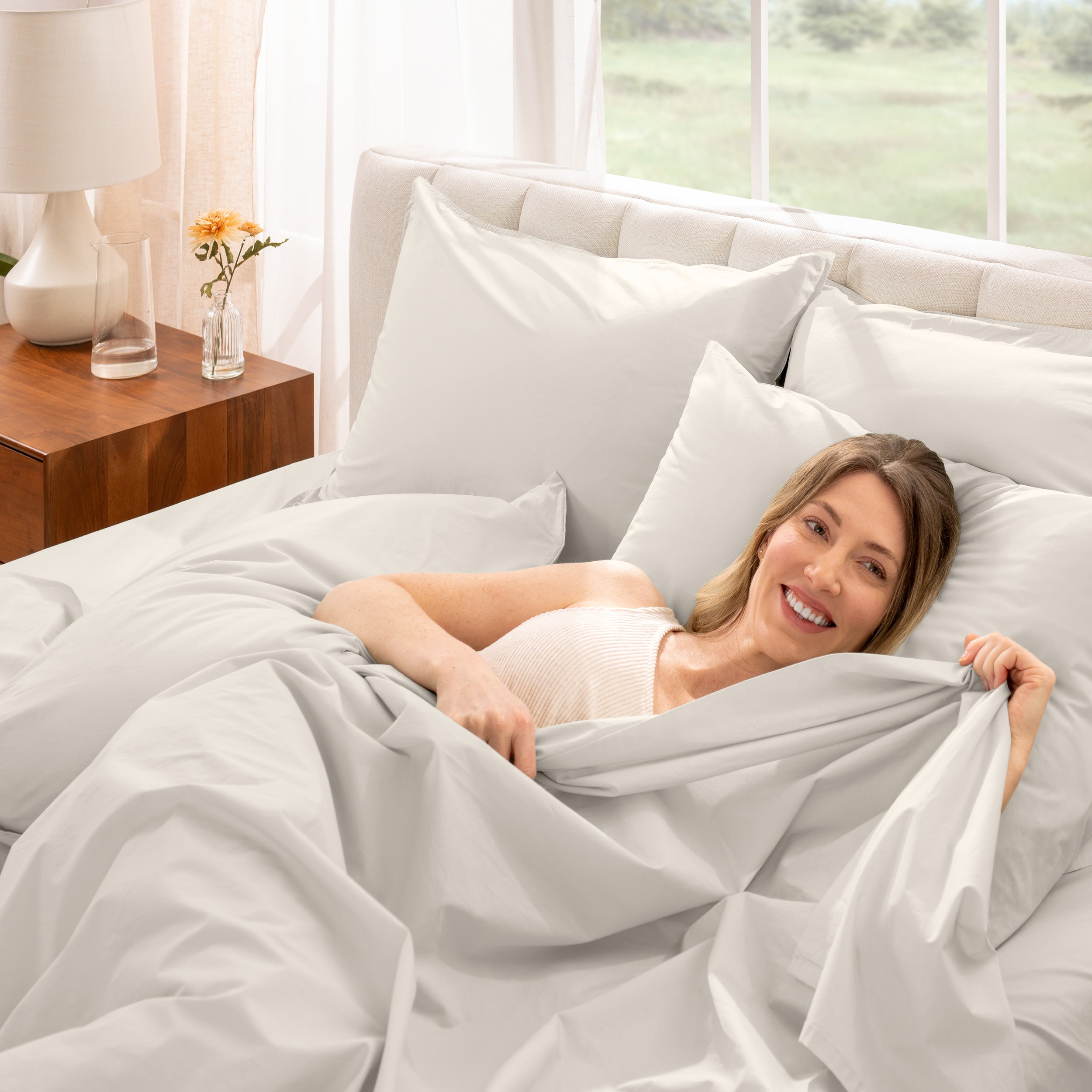 A woman is lying on a bed make with percale sheets and pillowcases