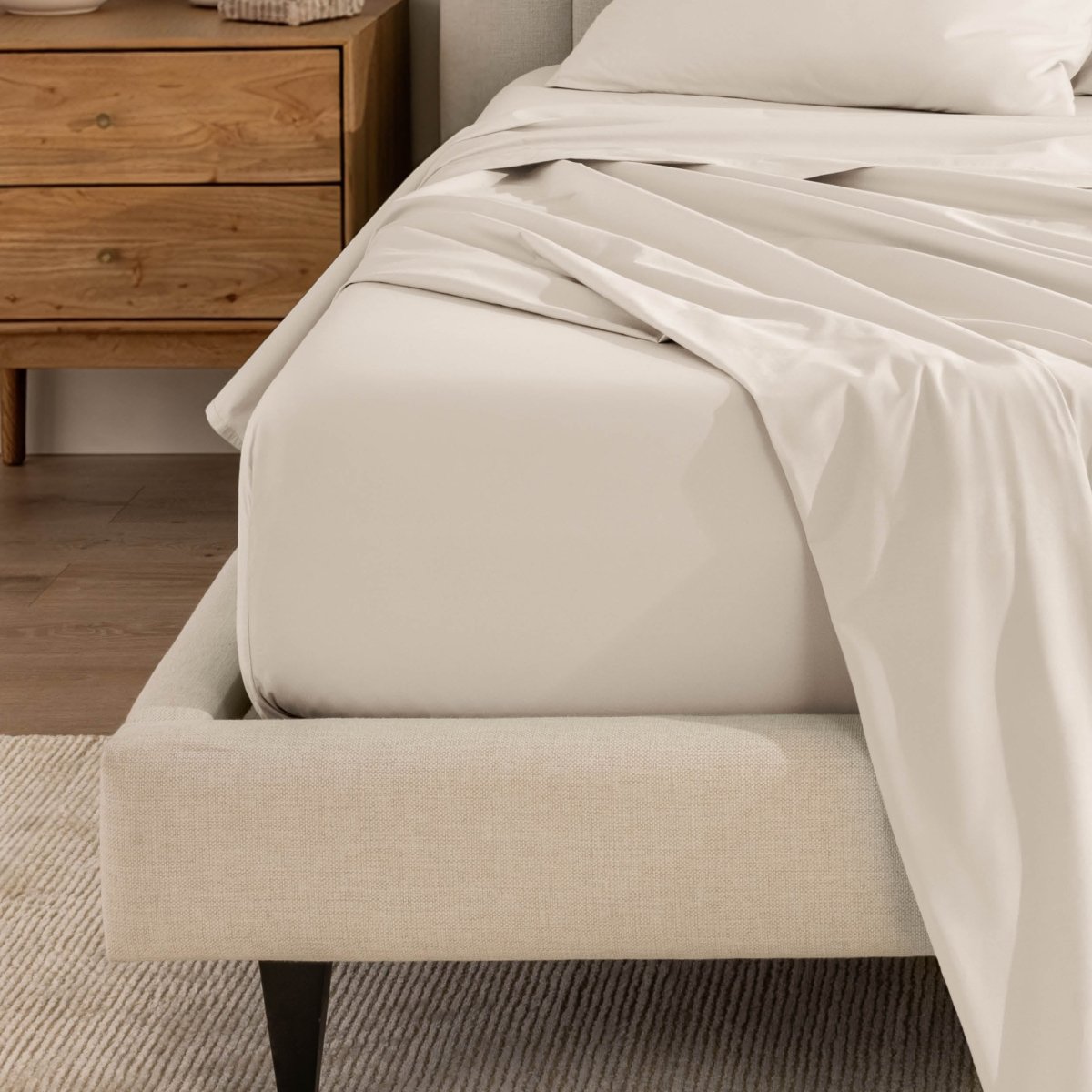 Top sheet and a matching fitted sheet on a bed with a beige bed frame