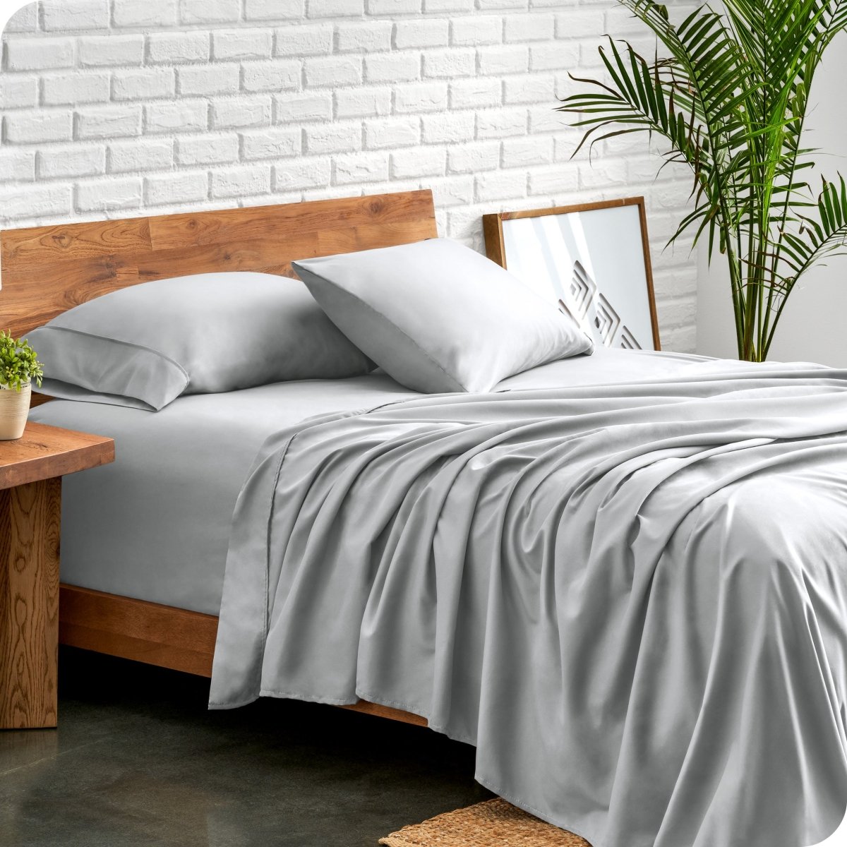Bed with microfiber sheets against a white brick wall