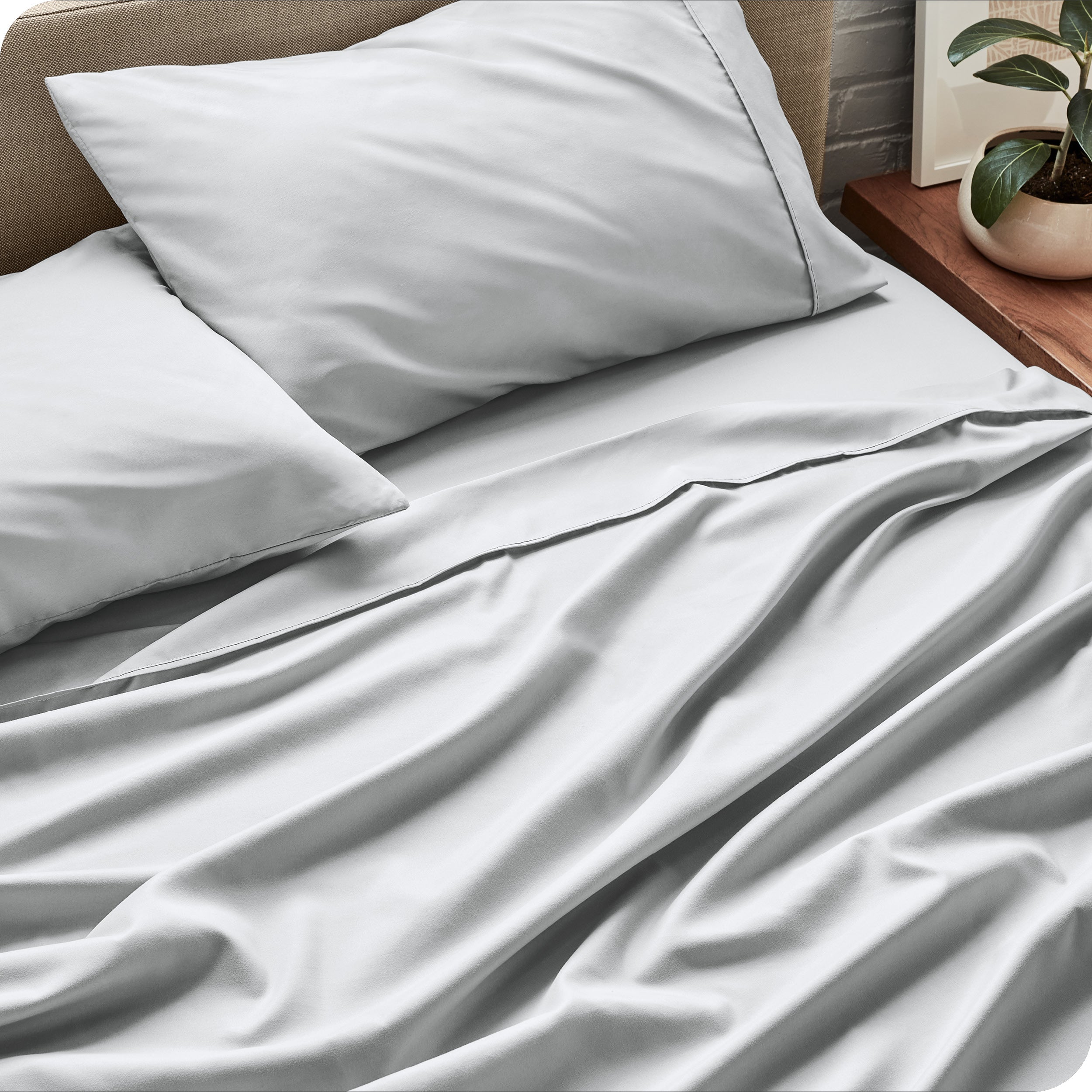 Sheet set on a bed with pillows and a plant in the background