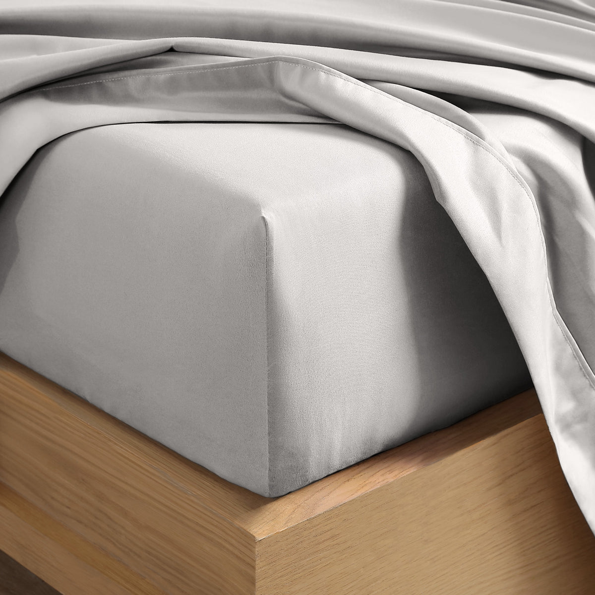 Close up of the corner of a mattress with a fitted sheet and flat sheet on it