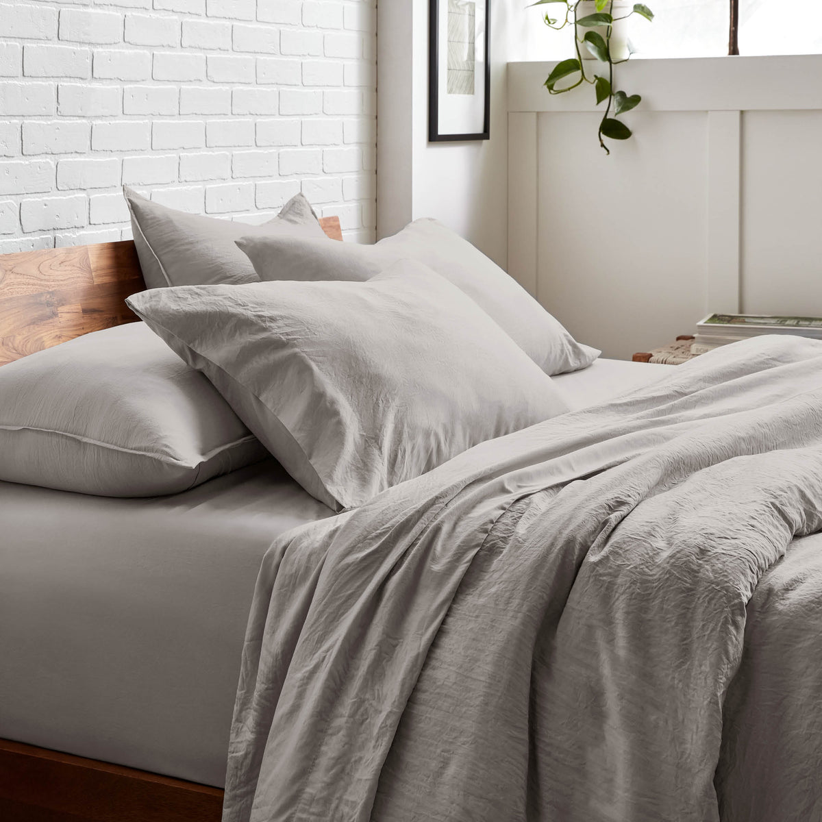 Bedding set on a bed with a white brick wall and window in the background