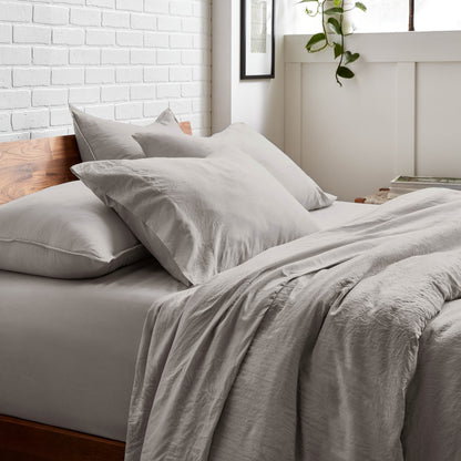Bedding set on a bed with a white brick wall and window in the background