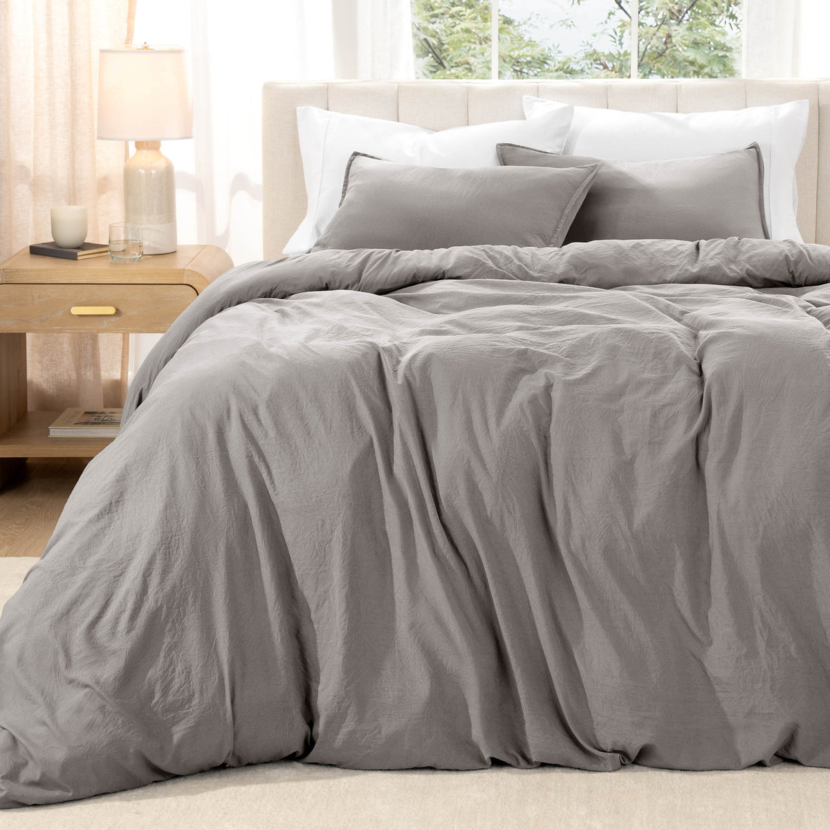 Bed with washed bedding and white pillows in a bright room