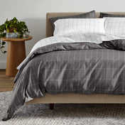 Bed with gray and white grid bedding in a bedroom setting.