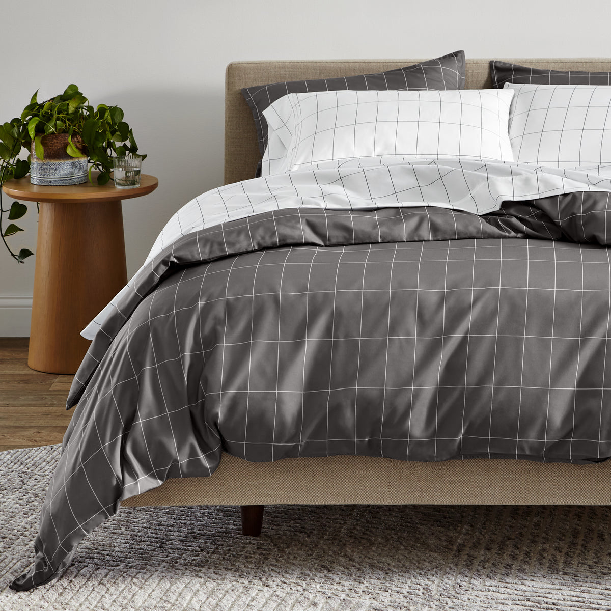 Bed with gray and white grid bedding in a bedroom setting.