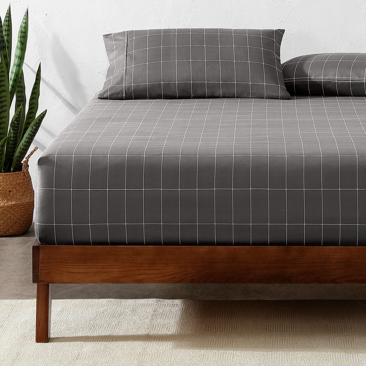 Bed with a fitted sheet with a plant next to it