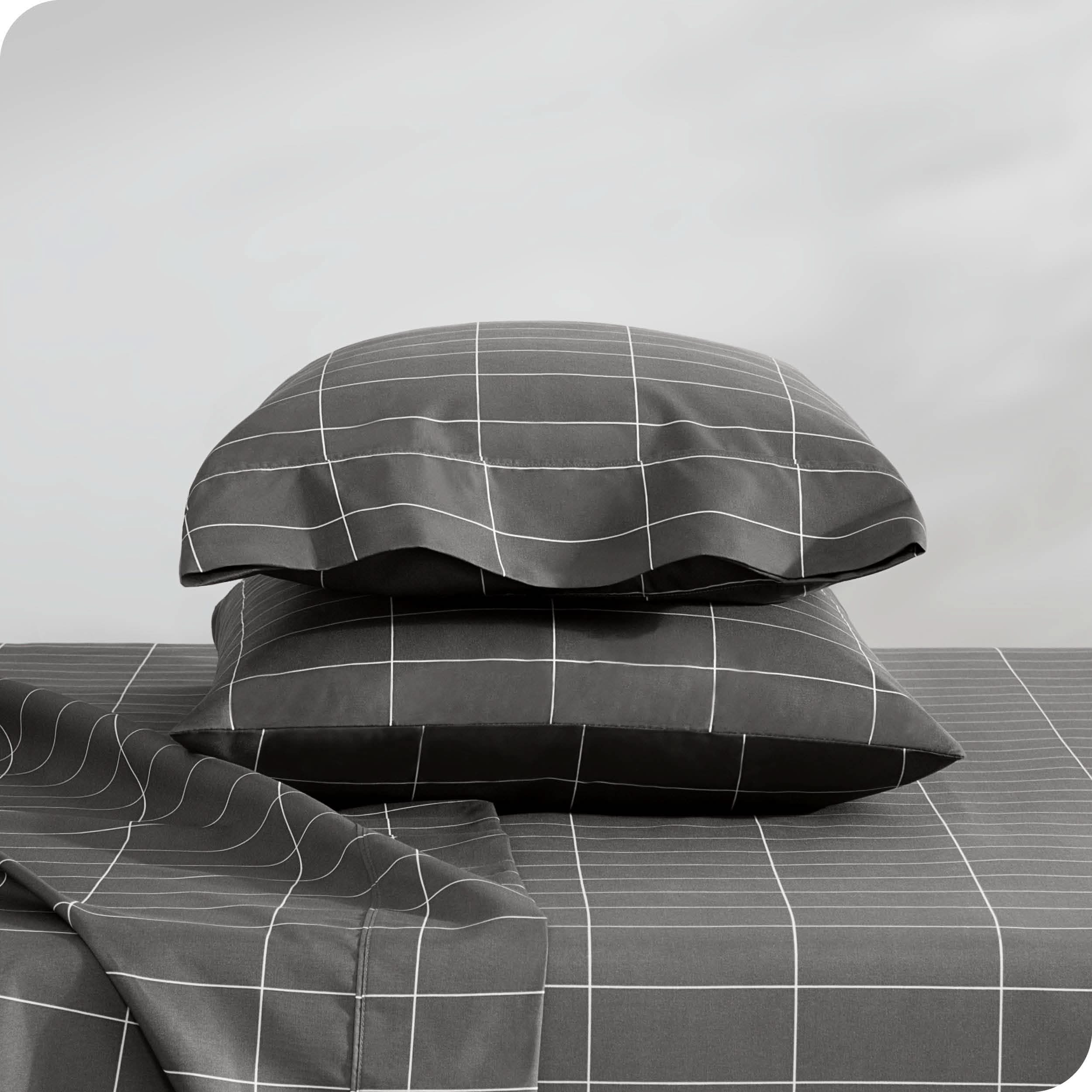 Two pillows with pillowcases on them stacked on a bed