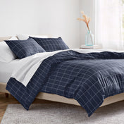 Navy blue grid patterned comforter on a bed in a bright bedroom.