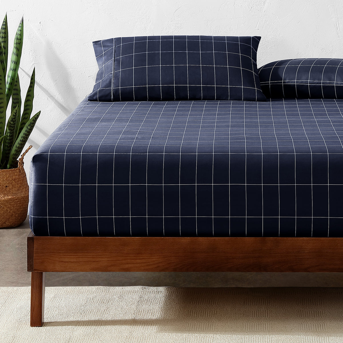 Bed with a fitted sheet with a plant next to it