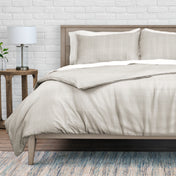 Neatly made bed with beige bedding in a bedroom setting.
